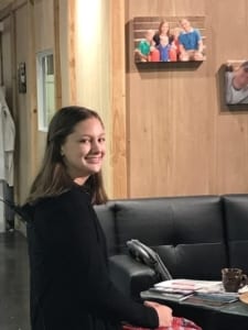 Young girl smiling at the camera sitting on a sofa.